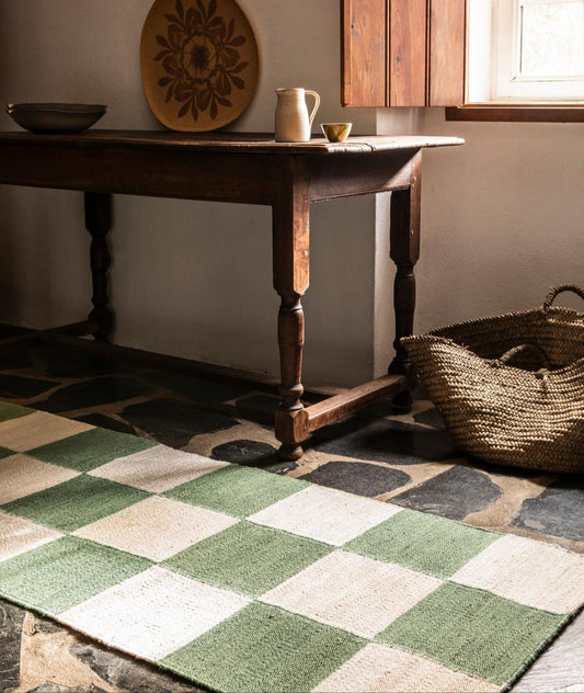 Designet kombinerer grafiske mønstre med tradisjonelt håndverk, og resulterer i en moderne tolkning av en tidløs stil. Teppe Sicilian Jute fra Layered i grønt rutemønster/Clover i størrelsen 75x240 cm.