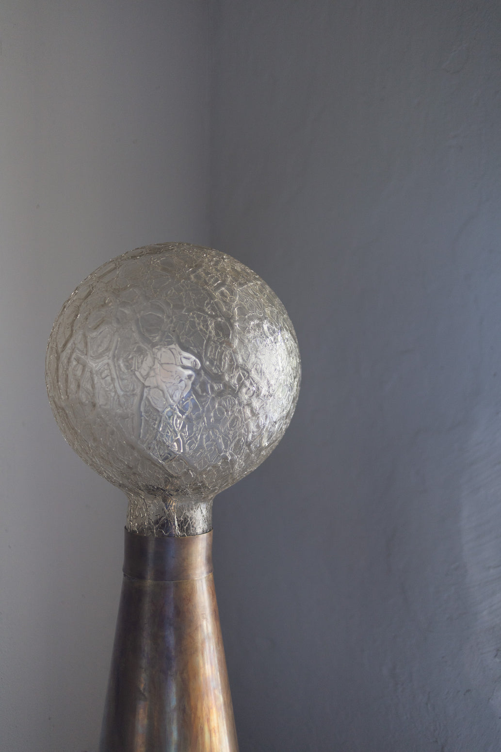 Kombinasjonen av materialene, formen og lyset den avgir er nesten magisk fin: På den store koniske lampefoten i patinert messing hviler en vakker glasskuppel, som med sine unike fasetteringer i glasset reflekterer lyset på nydelig vis når den er tent.