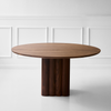 Spisebordet Plush Table rundt fra dk3 er et blikkfang med sitt solide, kubeformede bordben, med dekorative utsmykkede riller i heltre. Avbildet er en variant i valnøtt.