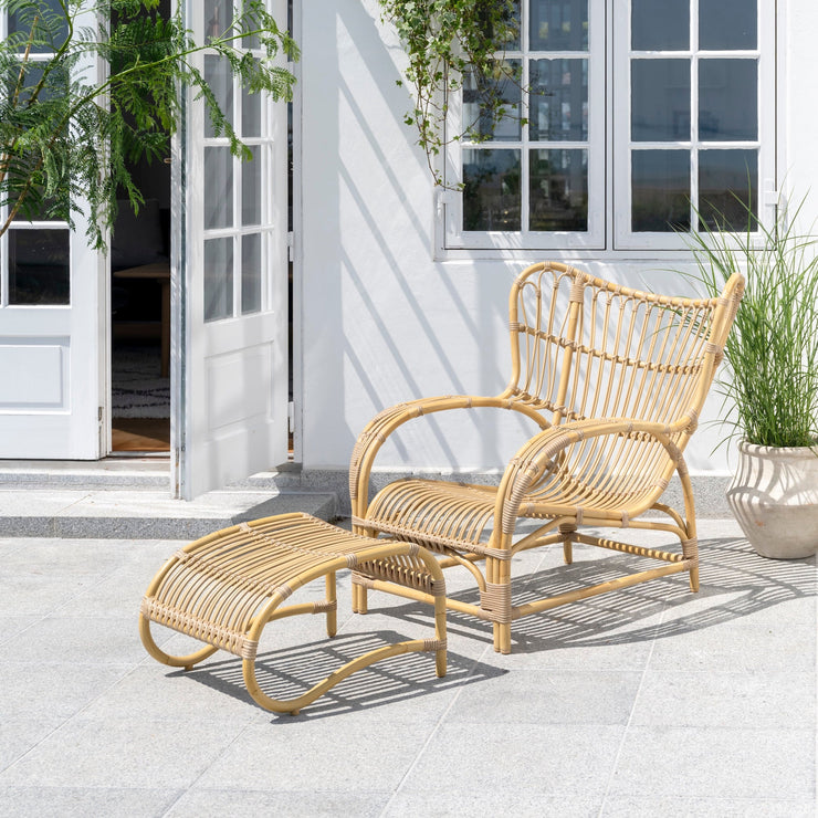 Teddy Lounge Chair og Teddy Footstool fra Sika Design på terrasse utendørs, naturfarget Alu-Rattan