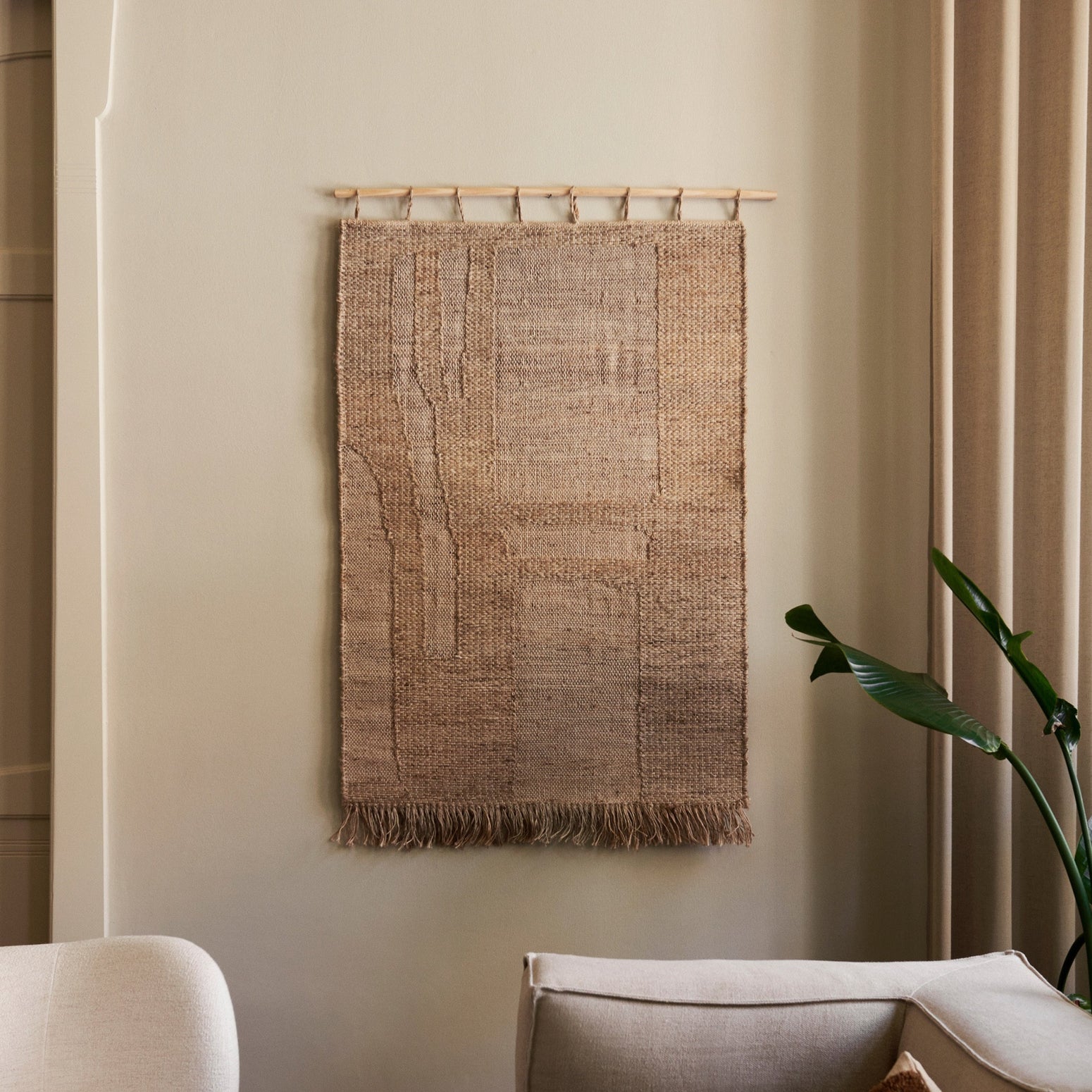 Veggteppet Harvest Wall Rug fra Ferm Living henger fra en rundstokk i bøk som gjør det enkelt å montere på veggen. Veggteppet kommer i to ulike størrelser.