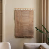Veggteppet Harvest Wall Rug fra Ferm Living henger fra en rundstokk i bøk som gjør det enkelt å montere på veggen. Veggteppet kommer i to ulike størrelser.