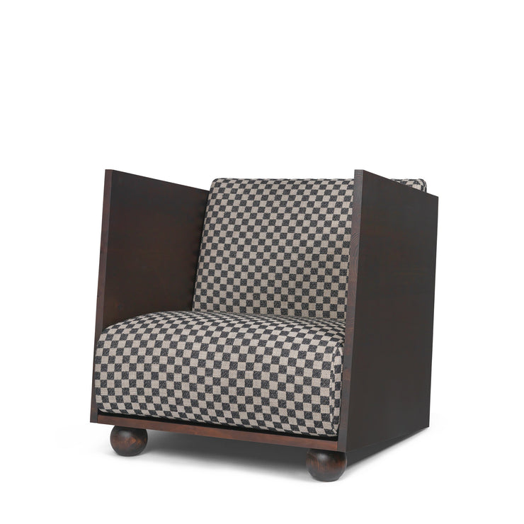 Rammen til lenestolen Rum Lounge Chair fra Ferm Living er laget i oljet og beiset furu. Tekstilet her er et svart- og sandfarget rutemønster.