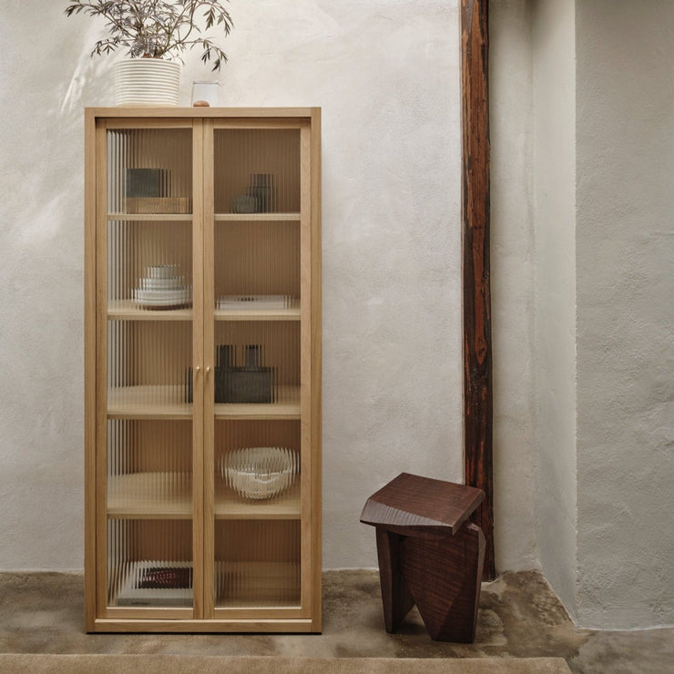 Vitrineskapet Reed Vitrine fra Ferm Living er et superfint vitrineskap i solid eik og eikefiner med rillede glassdører og messinghåndtak. I tillegg til at glasset tillegger vitrineskapet tekstur samtidig som innholdet skjules på en subtil måte, slipper det også lyset inn fra siden, og gjør skapet lett og sofistikert i uttrykket.