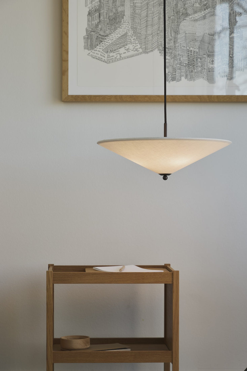 Futé 400 Tipp er en pendellampe fra Lyfa med en rund, konveks skjerm i et kremfarget kanvastekstil med detaljer i brunert messing, designet av det dansk-italienske studioet GamFratesi.