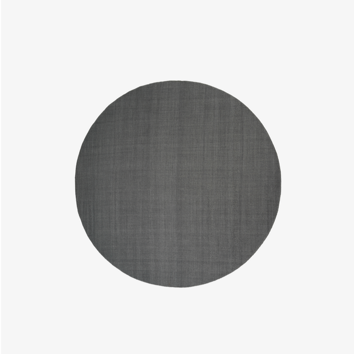 Found rug 05, stone grey. Teppet er rundt, laget i ren ull, og har en steingrå farge