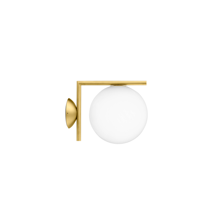 Den vakre vegglampen IC C/ W1 messing fra Flos, er en klassisk lampe med en moderne form. Glasskuppelen balanserer perfekt på kanten av en stang, noe designeren Michael Anastassiades utforsker gjennom hele lampeserien IC, som består av bord-, vegg- og taklamper.