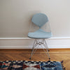 Denne skulpturelle stolen har et polstret sete og rygg i stoffet Hopsak Ice Blue/Ivory.