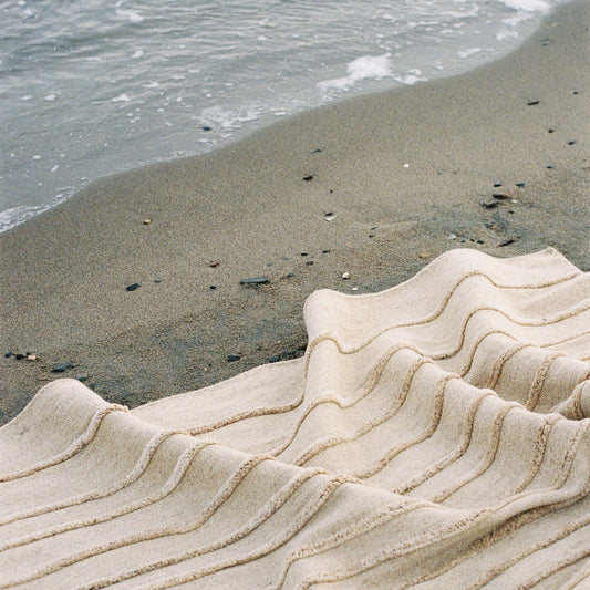 Naturinspirert gulvteppe i ren ull. Mønsteret i Sand-teppet er inspirert av når mønsteret som oppstår når bølgene har trukket seg tilbake, og etterlater ujevne riller i sanden.