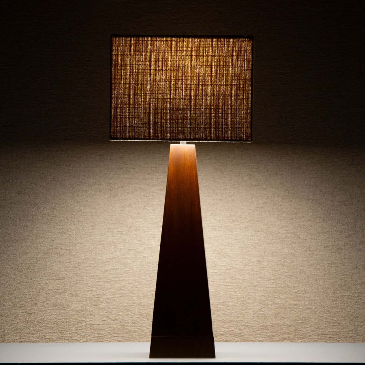 Takket være den beige tekstilskjermen avgir lampen et deilig, mykt og dempet lys som spiller på lag med og fremhever det mørke treverket.