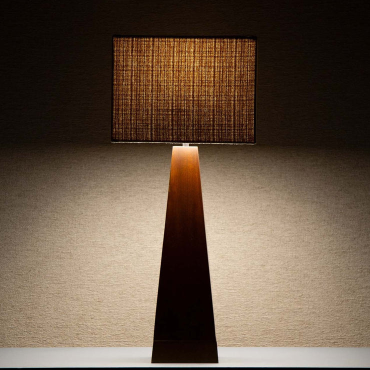 Takket være den beige tekstilskjermen avgir lampen et deilig, mykt og dempet lys som spiller på lag med og fremhever det mørke treverket.