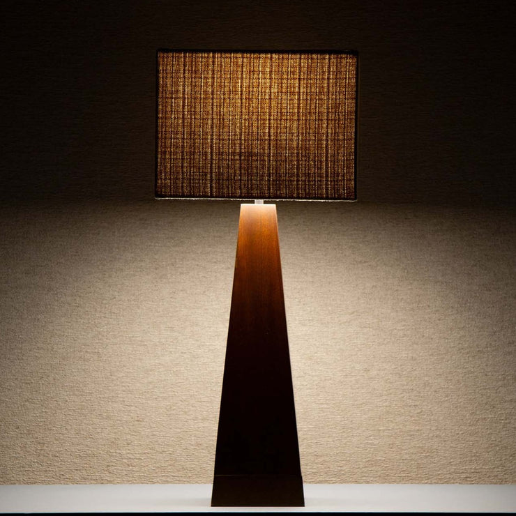 Takket være den beige tekstilskjermen avgir lampen et deilig, mykt og dempet lys som spiller på lag med og fremhever det mørke treverket.
