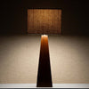 Takket være den beige tekstilskjermen avgir lampen et deilig, mykt og dempet lys som spiller på lag med og fremhever det mørke treverket.
