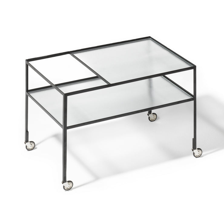 Herbert Hirche designet Bar Wagon i 1956. Dette minimalistiske sidebordet har en herlig kontrast i rillet glass og tynt stål, og den lagvise oppbyggingen gir rom for barsamlingen, bøker, og annet du måtte ønske å sette til utstilling på dette stilige bordet