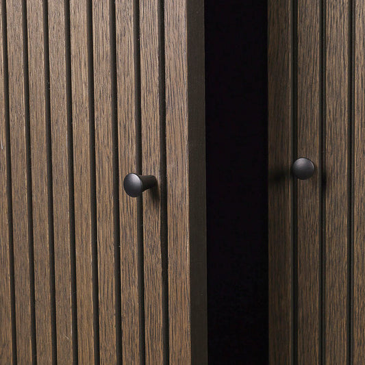 Skapet Sill Cupboard er laget i mørkt treverk, og har dekorative riller på dørene. 