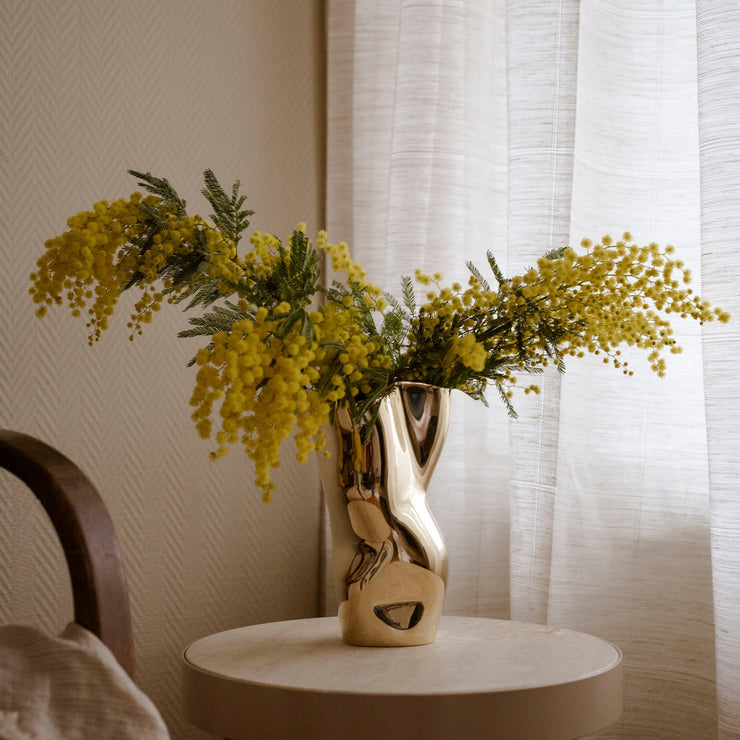 Vase i messing, som gjør vakre blomster enda vakrere. Gul mimosa, for eksempel! Vasen Ostrea Gold fra Hein Studio. 